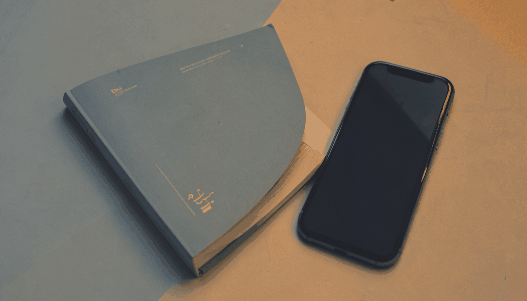 A warm duotone photograph of a technology guidebook beside a smartphone, in muted slate-blue and amber tones.